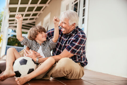 Grandfather and grandson celebrate soccer win on porch