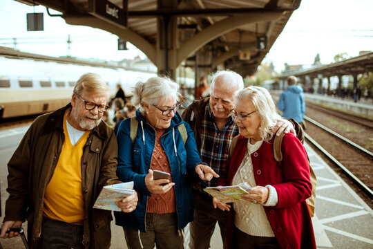 Senior friends planning trip at train station platform