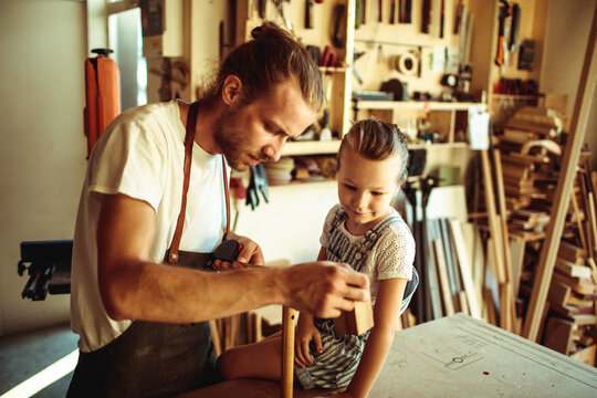 Father teaching daughter woodworking in home workshop