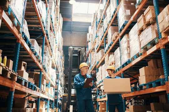 Two warehouse workers checking inventory in distribution center aisle