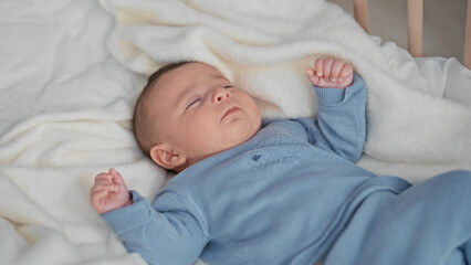 Hispanic newborn baby lying in crib on white blanket raising hand and kicking foot in studio  calm comfort bonding. © Krakenimages.com