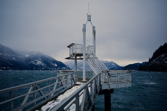 Stormy sea by the pier with mountains in the background