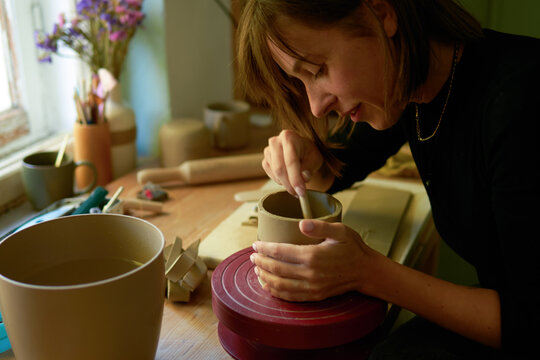 A potter smooths the interior of a hand-built clay cup