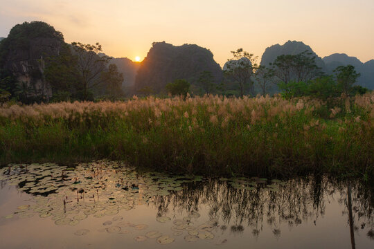 Sun sets behind limestone karst mountains in Ninh Binh 