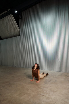 Dancer Stretches on the Floor in an Empty Studio With Gray Walls