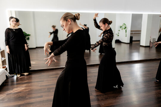 Women practicing expressive flamenco dance movements in studio