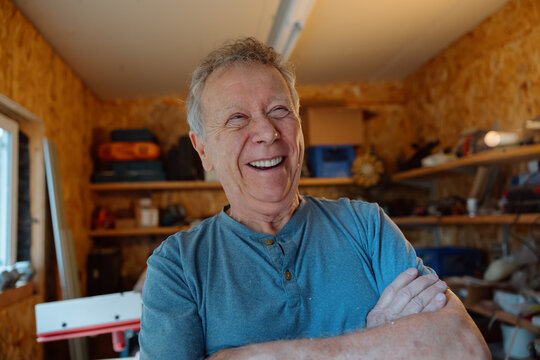 Candid happy retiree enjoying woodworking in his home workshop