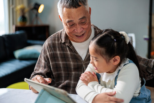 Grandfather and granddaughter bond over a tablet together.