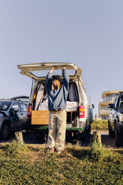 UGC Woman stretching at open back of van during autumn beach morning