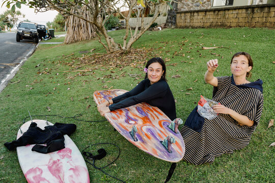 UGC Post surf friends sitting on grass eating grapes with surfboards