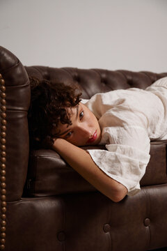Woman Resting on a Brown Couch During a Quiet Indoor Moment