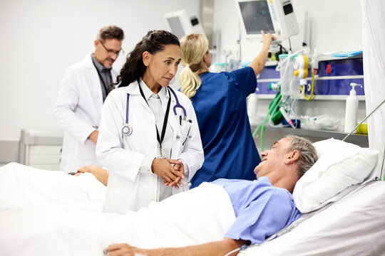 Doctor and Nurse Talk by Hospital Bed