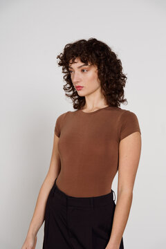 Model Poses in Studio Wearing Brown Top and Black Skirt