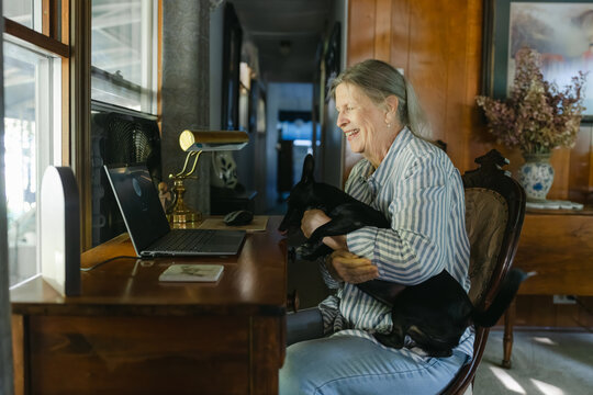 woman sitting at her desk with dog on her lap 