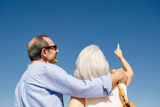 Senior couple pointing toward future under blue summer sky copyspace