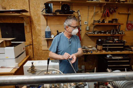 Senior woodworker wearing mask working in workshop