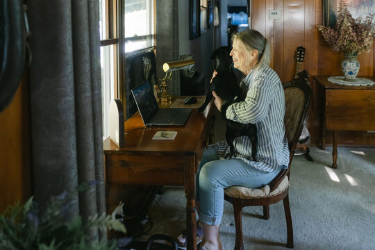 woman sitting at her desk with dog on her lap 