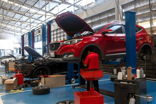 Professional Automotive Repair Service with Mechanic Working on Elevated Car