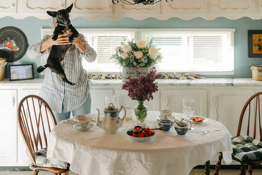 woman holding her dog while having tea at table