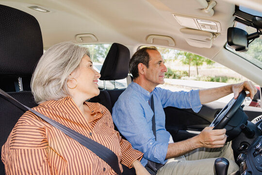 Mature senior couple riding in car during candid neighborhood drive
