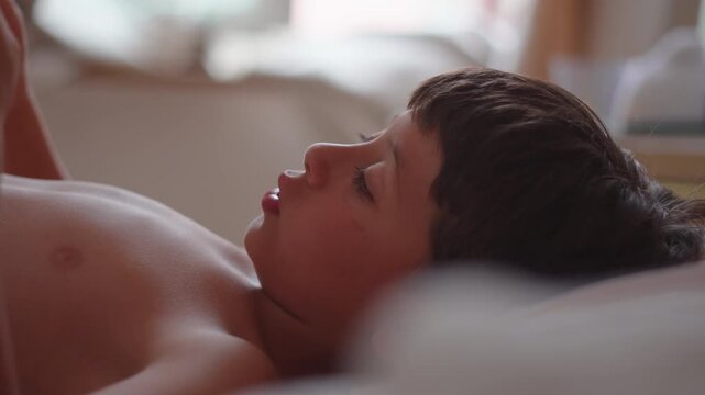 Boy reading book in bed close up at home, highlighting concentration, literacy and peaceful childhood development