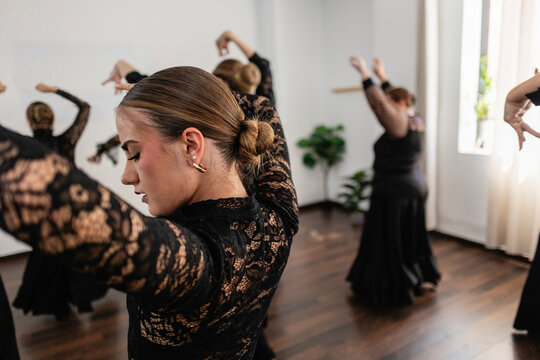Female flamenco dancer performing with group in studio