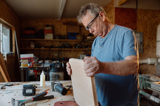 Senior carpenter inspecting a wooden board in workshop