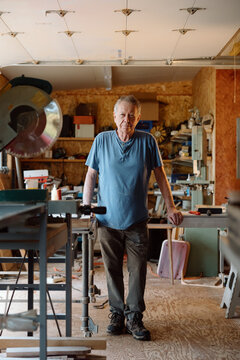 Candid portrait of a senior woodworker in his home workshop