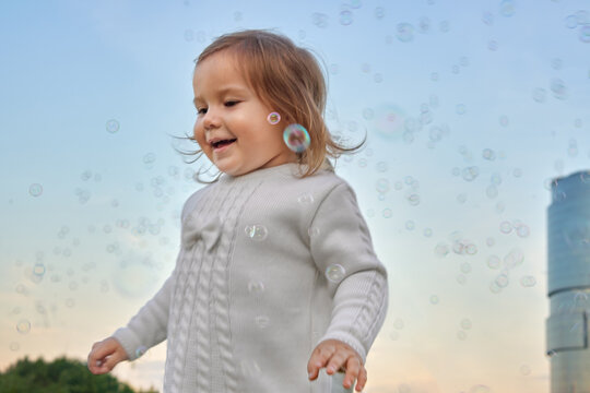 Toddler Playing with Soap Bubbles Outdoors at Sunset