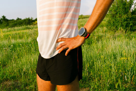 Runner in Sports Attire Stands in Field During Sunset
