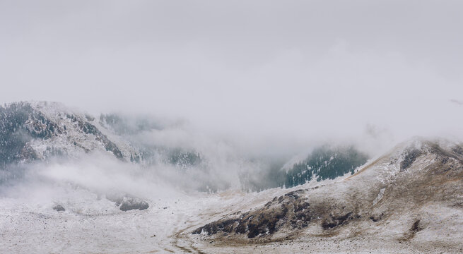 A Mountain Valley Enveloped by Clouds and Mist in a Snowstorm.