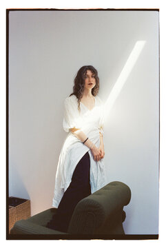Girl stands by the wall with light in a studio space