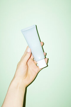 Hand holding a grey cosmetic beauty product lotion cream tube 