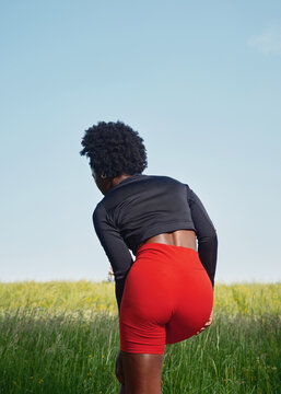 Person Stretches in Grassy Field Under Clear Sky in Summer