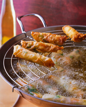Cooking spring rolls in hot oil in a frying pan