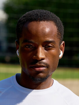 Man Wearing Earbuds Enjoying Activity Outdoors in Bright Light