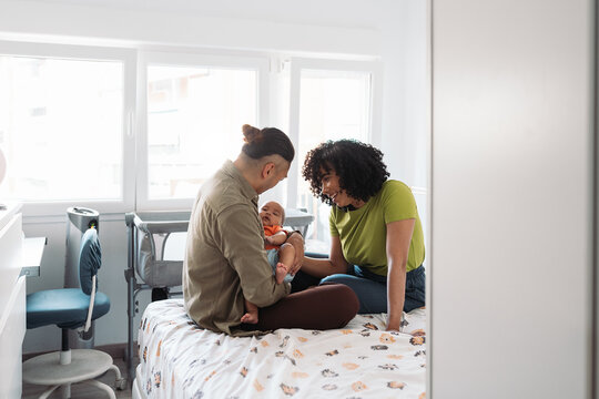 Diverse family bonding with newborn baby at home