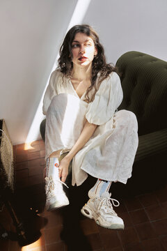 Woman sitting in studio during daytime wearing white outfit