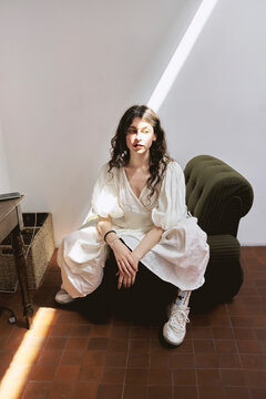 Young woman sits in studio with natural light from window