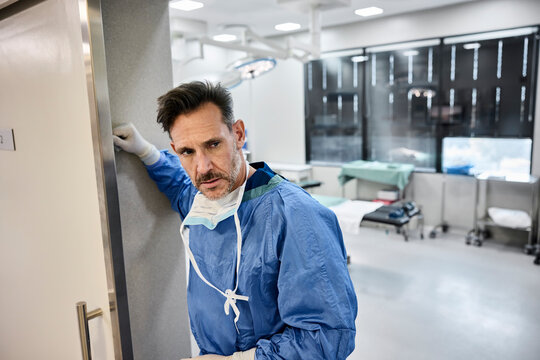 Tired Surgeon leans against door in operating room