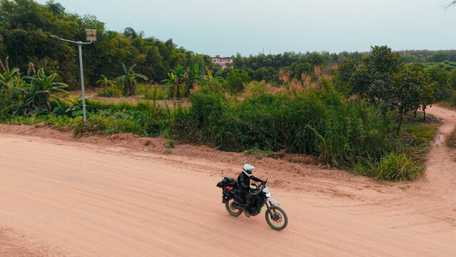 Motorbiker on a dirt road through rural Pluak Daeng