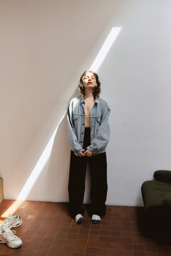 Girl stands in studio with sunlight streaming through window