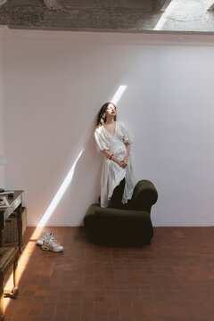 Woman standing in studio with light streaming through window