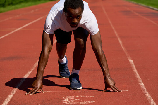 Runner Prepares to Start Race on a Track in Bright Sunlight