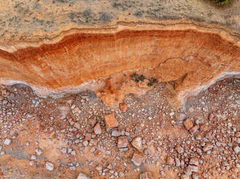 Colorful eroded cliff face above rocks on a narrow beach