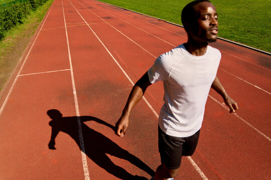Runner Moves on Track Under Sunlight in Training Session