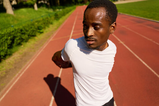 Runner Stretches on an Outdoor Track During Daylight Hours