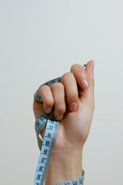 Hand tightly gripping a blue measuring tape, symbolizing control
