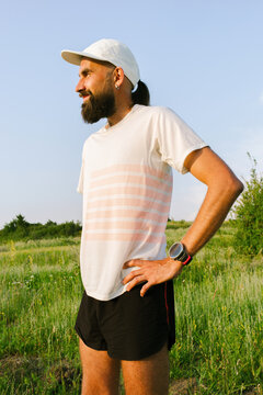 Male Runner Stands in the Field Wearing Sports Clothes During the Day