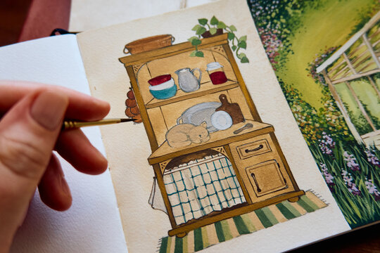 Close-up of an artist painting a cozy kitchen and garden illustration